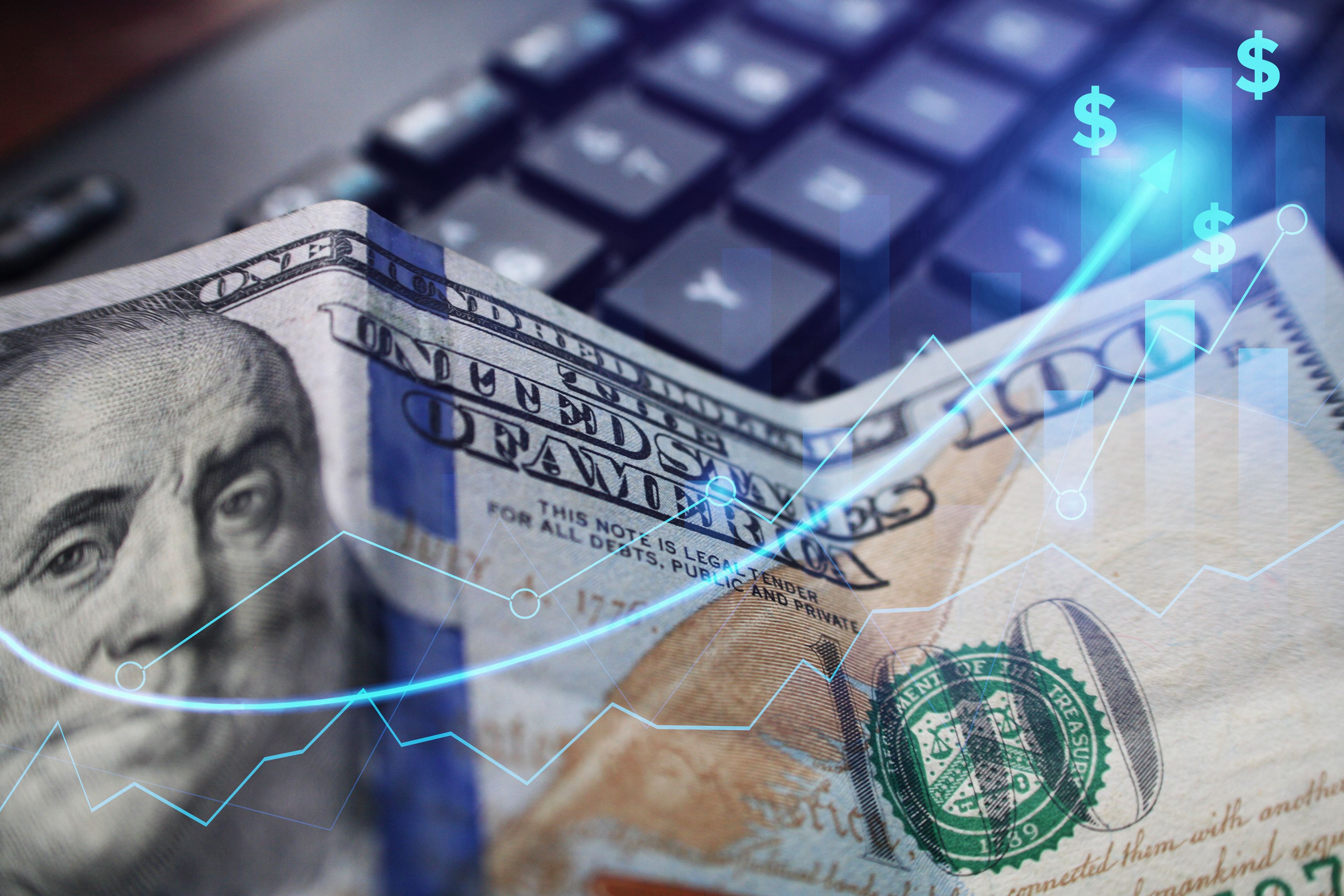 100 dollar bill sitting on keyboard with rising graph overlaid