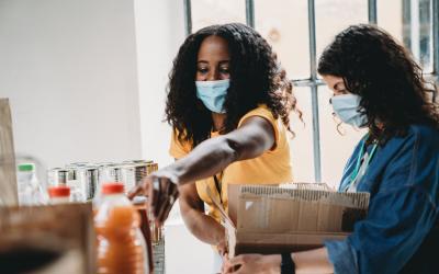 two women with masks on working at food donation charity event