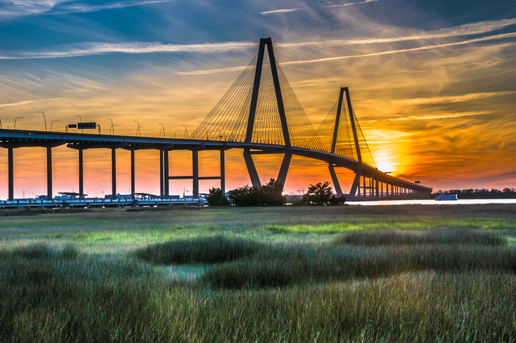 Photo of a vehicular bridge crossing a river at sunset.