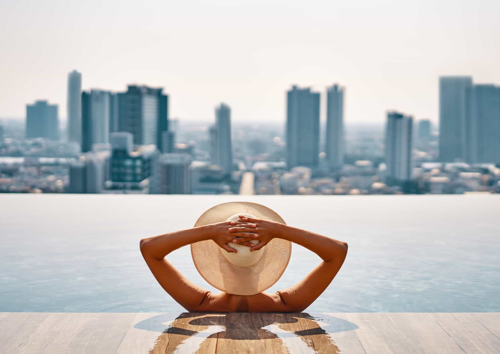 woman in rooftop infinity pool with sunhat on
