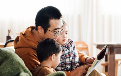 father with two children reading a picture book