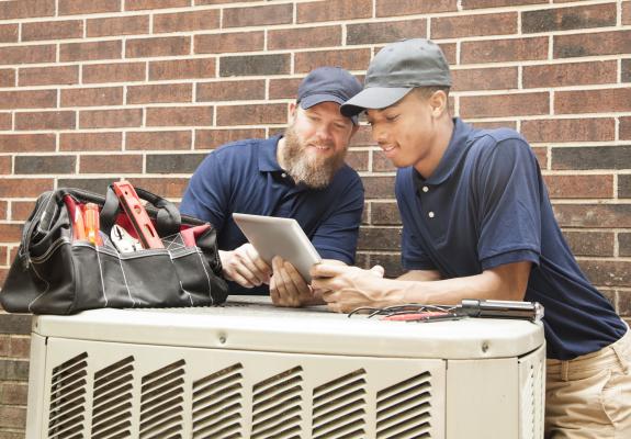 two maintenance men repairing an air conditioner