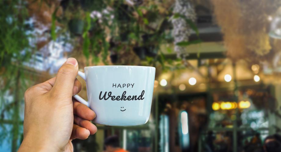 man's hand holding mug that says "happy weekend"