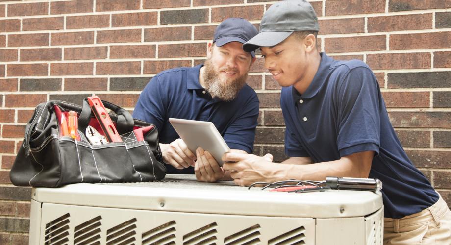 two maintenance men repairing an air conditioner