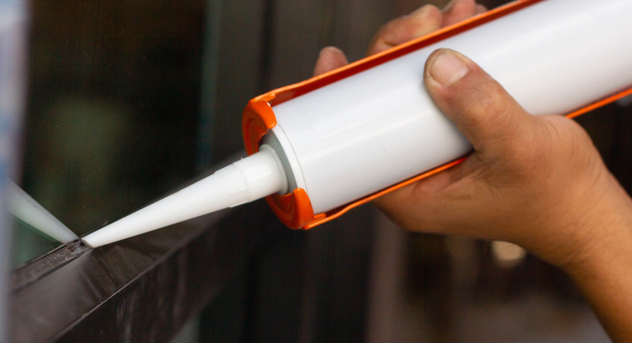 maintenance person caulking the seam of a vent