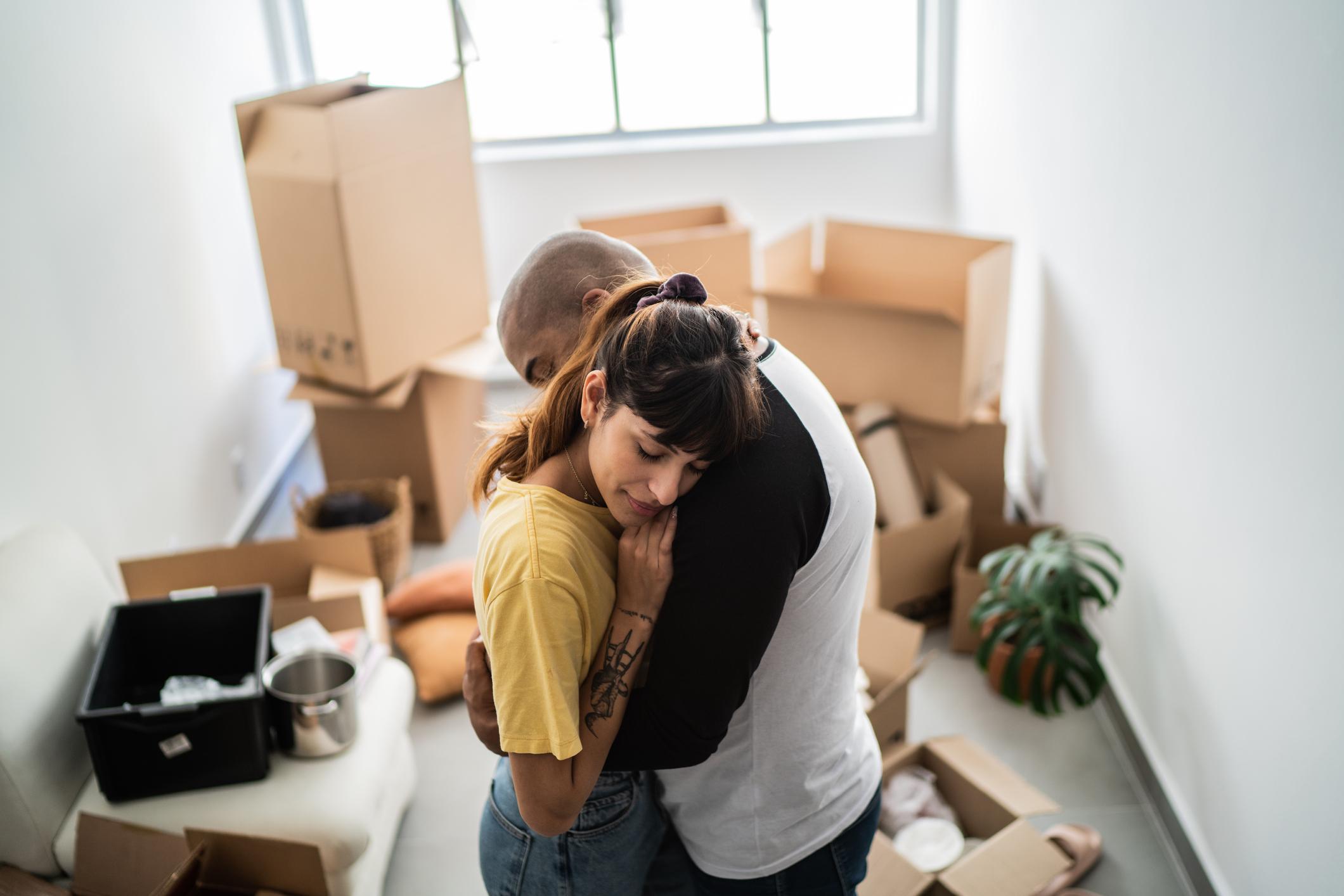 couple hugging in an apartment with moving boxes around them